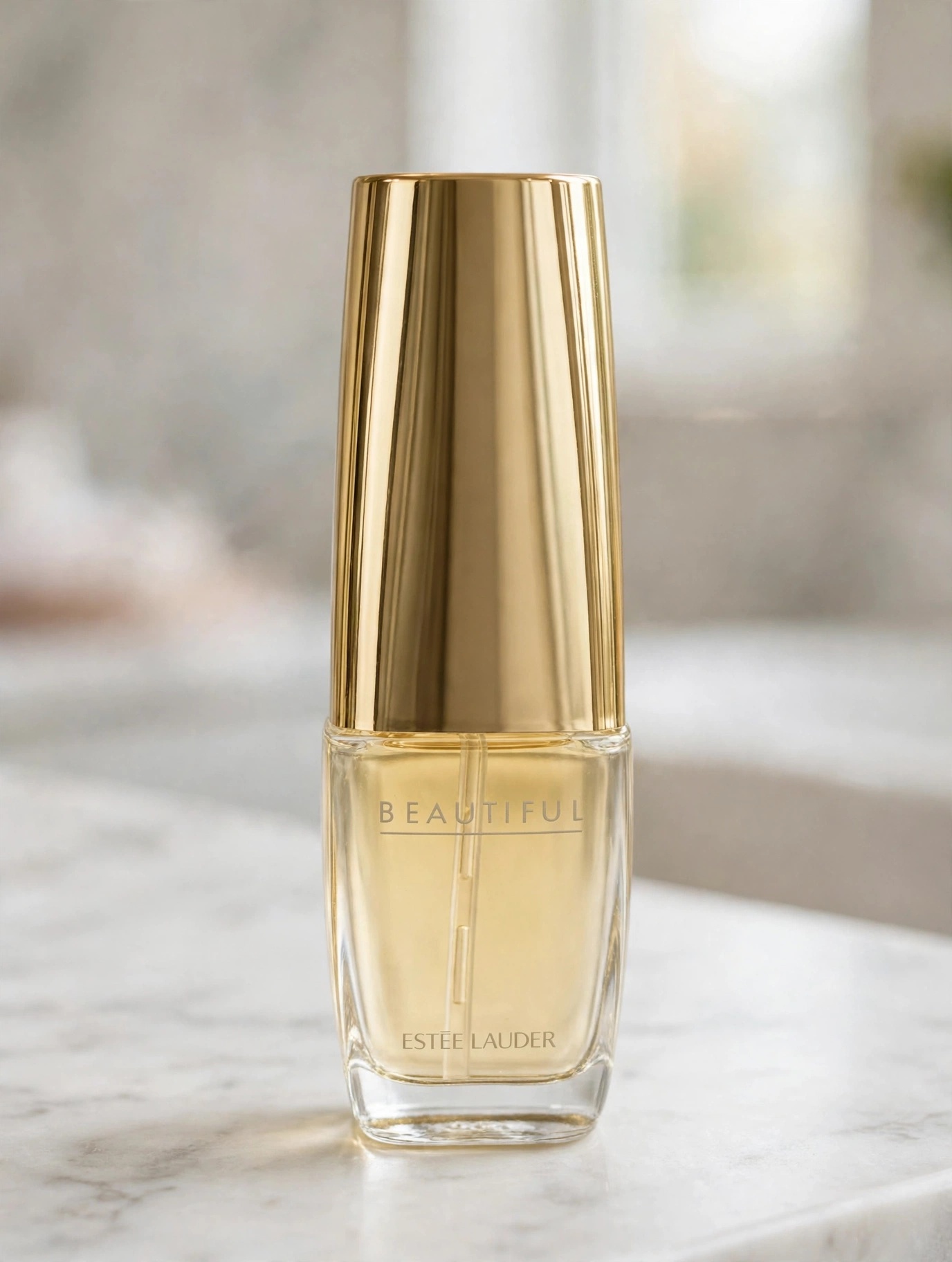 The Estée Lauder Beautiful eau de parfum bottle with its tall gold cap standing on a marble bathroom counter